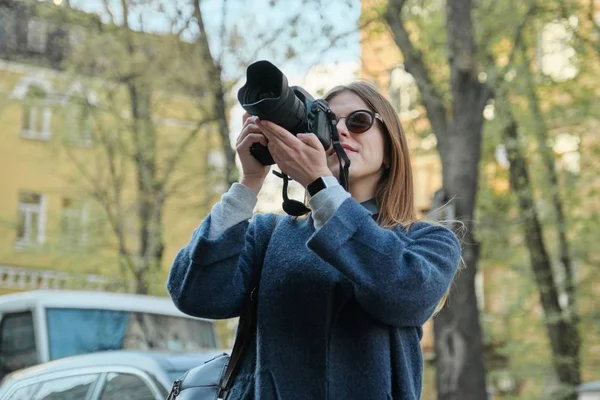 Schöne junge Frau mit Kamera in der Stadt. Touristenmädchen reisen und fotografieren, Frühling Stadt Straße Hintergrund — Stockfoto