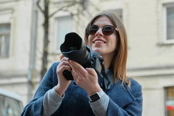 Fiatal gyönyörű lány fényképezőgéppel a tavaszi városban, lány turista fényképez a város utcáján — Stock Fotó