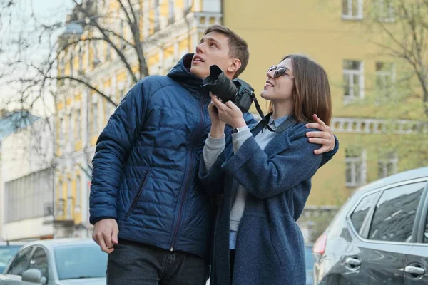 Pareja de turistas caminando en la ciudad, joven hermoso hombre y mujer tomando fotos en la cámara de fotos, ciudad de fondo en primavera —  Fotos de Stock