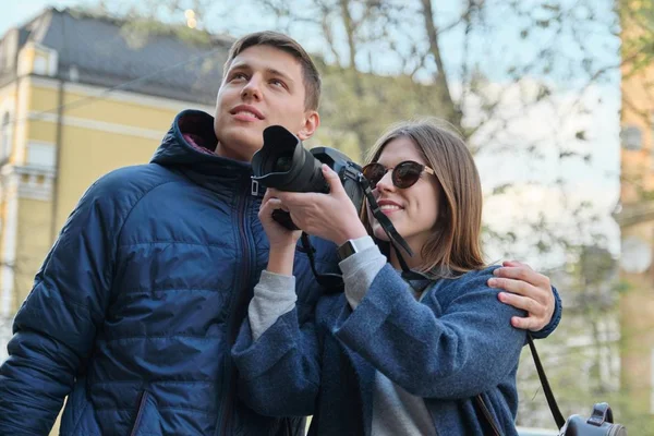 Junges glückliches Paar, das durch die Straßen der Frühlingsstadt geht, attraktive männliche und weibliche Touristen, die Fotos mit der Fotokamera machen — Stockfoto