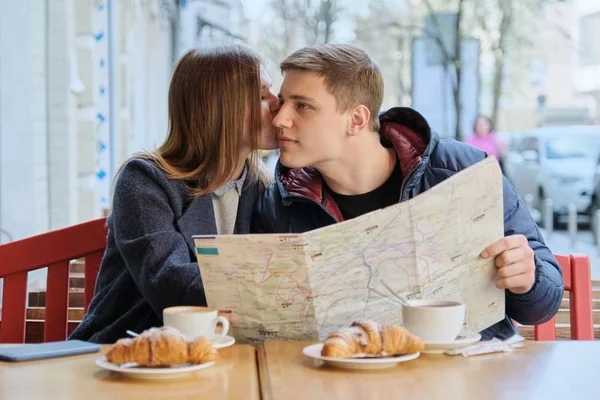 Joven pareja hermosa de turistas descansando en la cafetería al aire libre, leer el mapa de la ciudad, beber café con croissants . —  Fotos de Stock