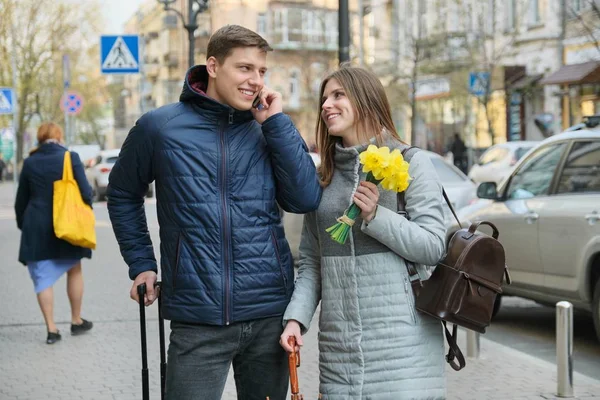 Δρόμος της πόλης της άνοιξης, ζευγάρι των νέων τουριστών με βαλίτσα, νέος άνθρωπος μιλάει στο τηλέφωνο, κορίτσι με μπουκέτο λουλουδιών — Φωτογραφία Αρχείου