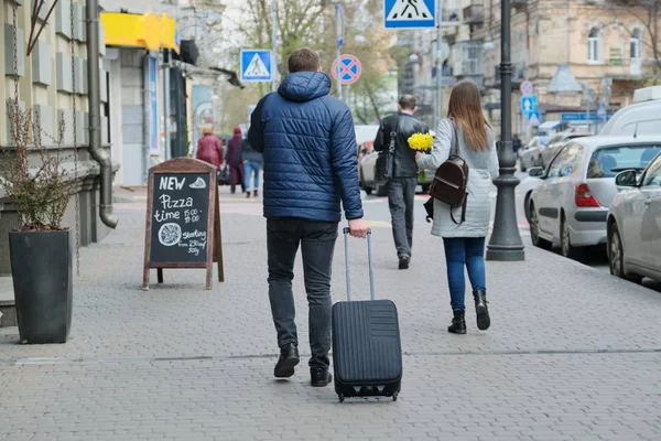 Homem de casaco com mala andando rua da cidade, vista para trás — Fotografia de Stock