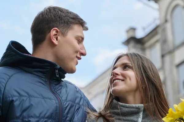 Retrato de primavera al aire libre de pareja joven caminando con ramo de flores amarillas de primavera narcisos, feliz juventud, fondo de calle de la ciudad —  Fotos de Stock