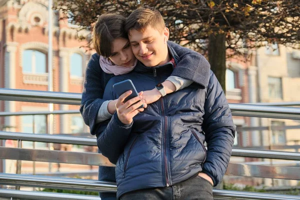 Jeune couple lisant du texte au téléphone, fond de la ville de printemps — Photo