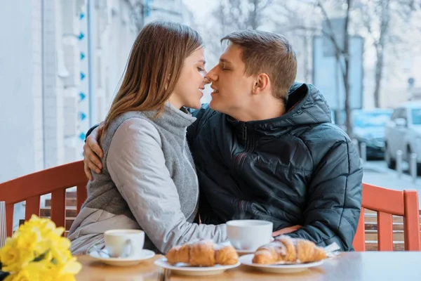 Jovem casal apaixonado no café ao ar livre, primavera buquê amarelo na mesa, café, croissants . — Fotografia de Stock