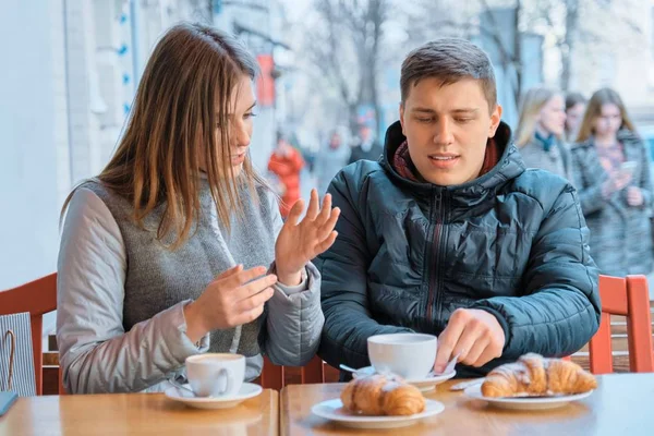 Young friends man and woman talking in outdoor cafe drinking tea coffee with croissants — 스톡 사진