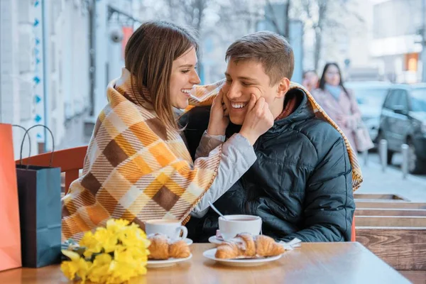 Alegre joven pareja en la cafetería al aire libre riendo y divirtiéndose bajo cuadros —  Fotos de Stock