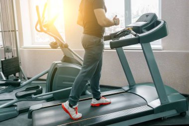 Modern spor salonunda koşu bandı üzerinde koşan atletik kaslı adam. Fitness, spor, eğitim, insanlar kavramı.