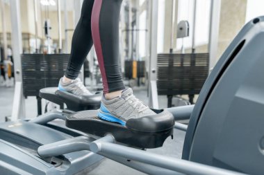 Spor salonunda koşu bandında koşan kadın ayaklarının yakın çekimi. Fitness, spor, eğitim, insan kavramı.