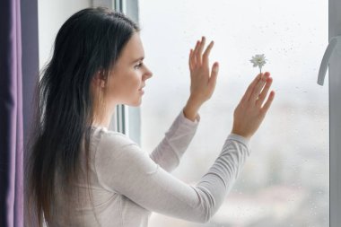 Genç gülümseyen kadın papatya ile arka plan yağmur damlaları, bitkisel Dermatoloji doğal güzelliği ile pencere