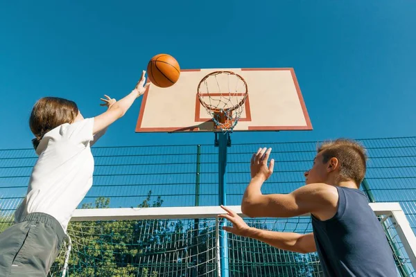 Streetball juego de baloncesto con dos jugadores, adolescentes niña y niño, mañana en la cancha de baloncesto —  Fotos de Stock