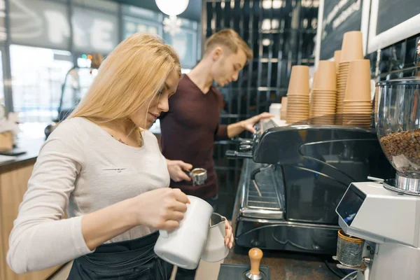 Jovem casal homem e mulher proprietários pequeno negócio café, trabalhando perto de máquinas de café, fazendo bebidas — Fotografia de Stock