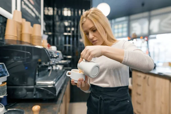 Café arte, close-up de jovem bela barista segurando leite para preparar xícara de café — Fotografia de Stock