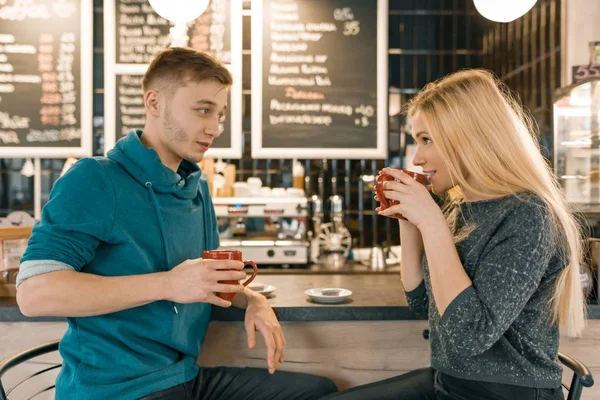 Joven sonriente hombre y mujer juntos hablando en la cafetería sentado cerca del mostrador del bar, un par de amigos tomando té, café — Foto de Stock