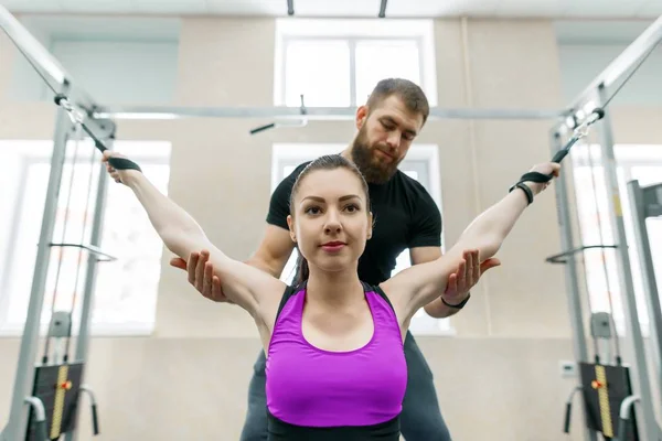 Kinesiotechnologie, Kinesiotherapie, gesunder Lebensstil. junge Frau macht Reha-Übungen mit persönlichem Trainer mit Kinesi-Gerät, Fitness-Studio Hintergrund — Stockfoto