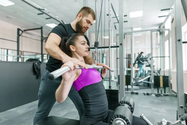 Entrenador personal de fitness que entrena y ayuda a la mujer cliente a hacer ejercicio en el gimnasio. Deporte, trabajo en equipo, entrenamiento, concepto de personas — Foto de Stock