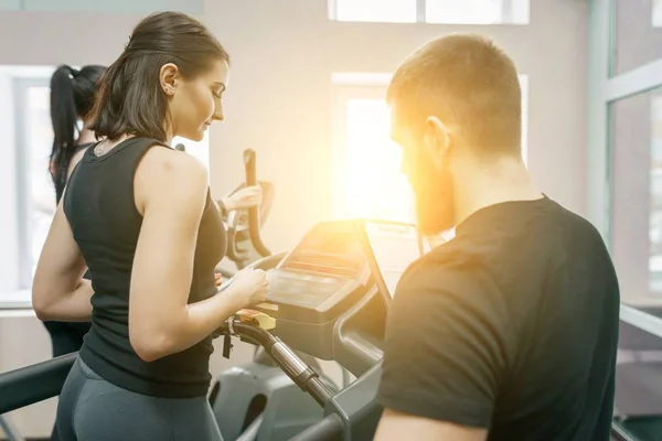 Mujeres atléticas jóvenes en la cinta de correr, instructor personal entrenando y ayudando a la mujer cliente. Fitness, deporte, entrenamiento, concepto de personas . — Foto de Stock