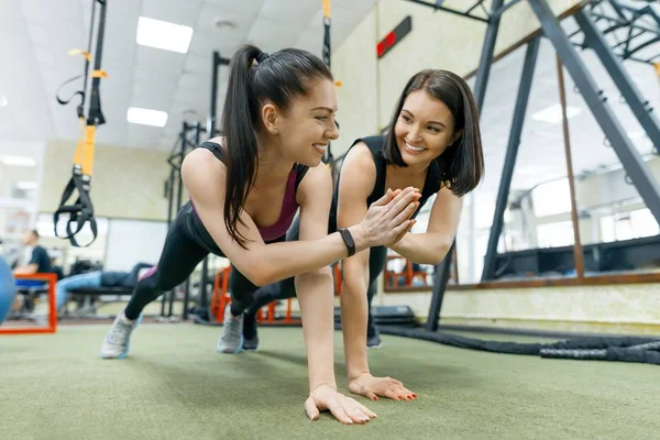 Duas jovens mulheres saudáveis se exercitando juntas no ginásio. Fitness, esporte, treinamento, pessoas, conceito de estilo de vida saudável . — Fotografia de Stock