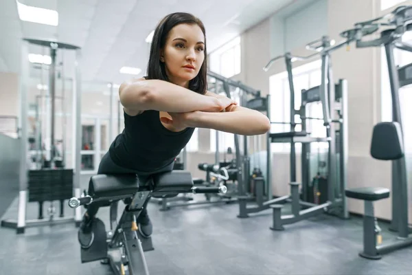Jeune femme sportive faisant de l'exercice sur les machines dans la salle de sport moderne. Fitness, sport, entraînement, personnes, mode de vie sain concept . — Photo