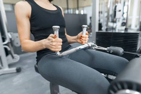 Mujer atlética joven haciendo ejercicio en las máquinas en el gimnasio deportivo moderno. Fitness, deporte, entrenamiento, personas, concepto de estilo de vida saludable . — Foto de Stock