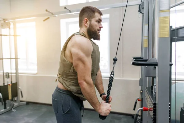 Muskulöser kaukasischer bärtiger Mann, der in gewichteter Weste in der Sporthalle Übungen macht, militärischer Stil — Stockfoto