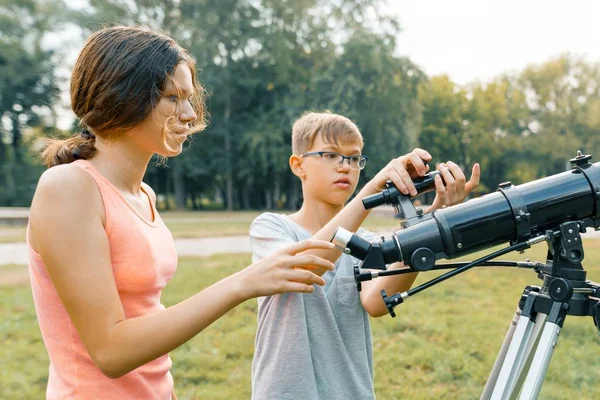 Niños adolescentes con telescopio miran al cielo en la naturaleza — Foto de Stock