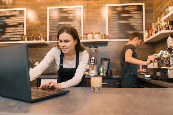 Equipe de trabalhadores da cafetaria que trabalham perto do balcão com computador portátil e fazendo café, negócio do café — Fotografia de Stock