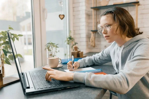 Ritratto di giovane studentessa, studentessa in caffetteria con computer portatile e tazza di caffè, la ragazza sta studiando, scrivendo nel quaderno — Foto Stock