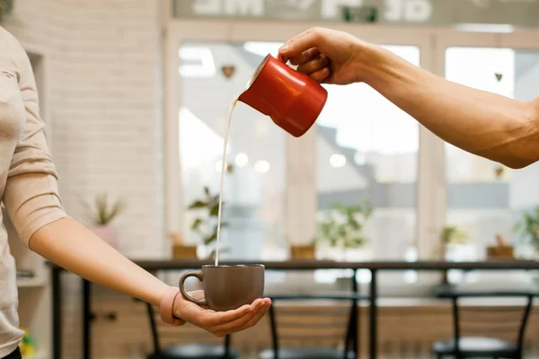 Primo piano di versare il latte cotto a vapore in tazza di caffè, sfondo caffetteria — Foto Stock