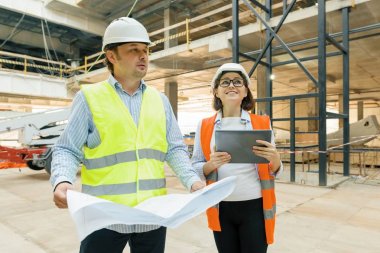 İnşaat alanında çalışan erkek bina işçileri, planlara bakan inşaatçılar. Bina, geliştirme, ekip çalışması ve insan konsepti