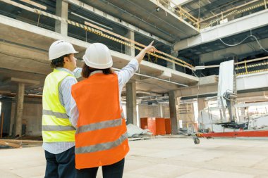 İnşaat alanında çalışan yapı işçileri, planlara bakan inşaatçılar, arka görünüm, kopya alanı. Bina, geliştirme, ekip çalışması ve insan konsepti