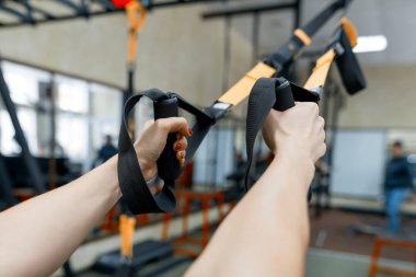 Yakın çekim spor salonunda fitness askıları ile eller. Eğitim, spor, fitness, insanlar kavramı.