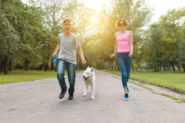 Parkta bir köpekle koşan gençler