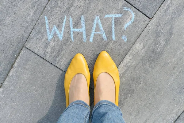 Abstrait quel point d'interrogation dessiné dans des crayons sur l'asphalte gris avec les jambes des femmes dans des chaussures jaunes — Photo
