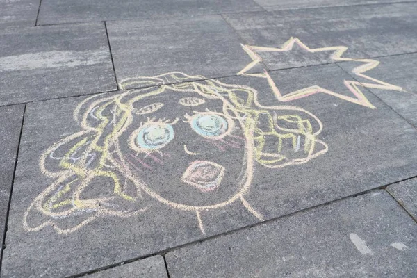 Abstract pop art woman face, picture written on gray sidewalk in crayons