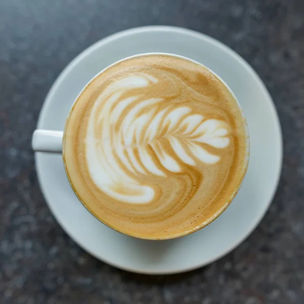 Кофе-арт в белой чашке с блюдцем на серой каменной поверхности стола — стоковое фото