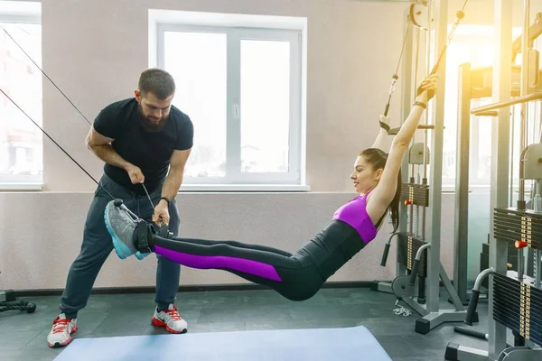 Tecnología de cinesis, kinesioterapia, estilo de vida saludable. Mujer joven haciendo ejercicios de rehabilitación con instructor personal utilizando la máquina kinesi — Foto de Stock