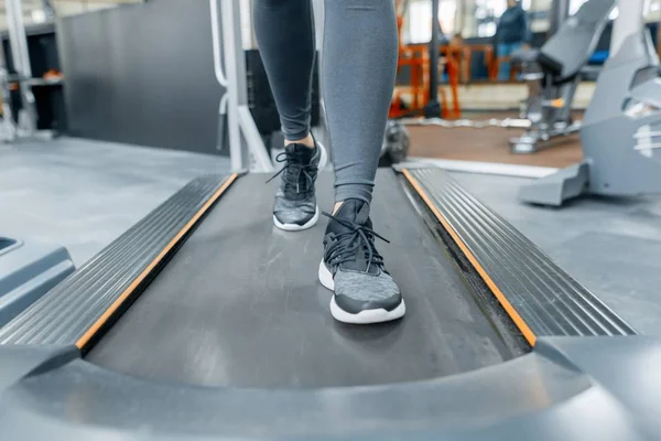 Primer plano de los pies de mujer corriendo en la cinta de correr en el gimnasio. Fitness, deporte, entrenamiento, concepto de personas . — Foto de Stock