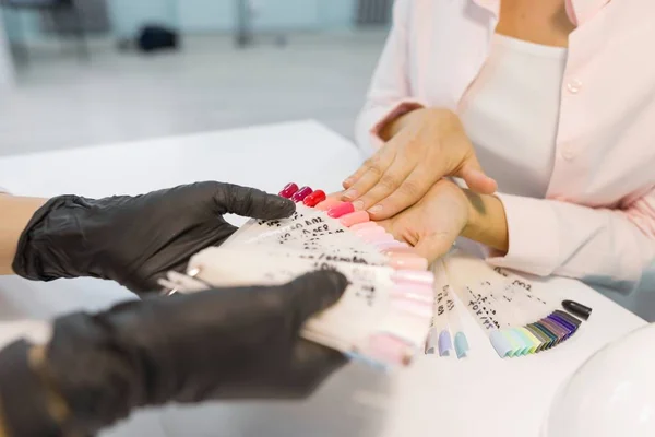 Крупный план женщины-клиента, выбирающей цвет лака для ногтей. Уход за ногтями и руками в салоне красоты — стоковое фото