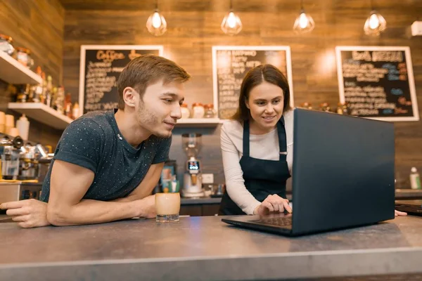 Giovani proprietari di coppia uomo e donna di piccola caffetteria moderna utilizzando il computer portatile per il lavoro — Foto Stock