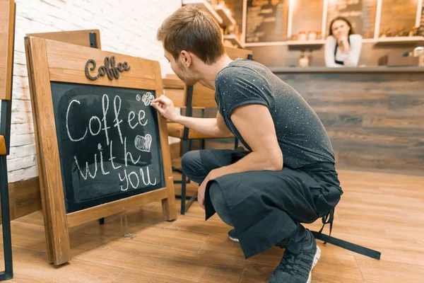 Café avec vous, écrit à la craie sur le tableau noir le jeune propriétaire masculin du café . — Photo