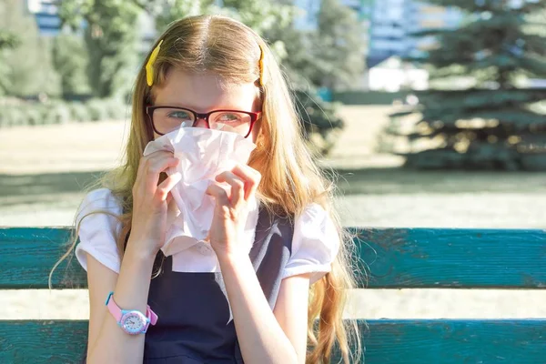 Gadis kecil yang duduk di taman bersin dengan saputangan, alergi musiman — Stok Foto