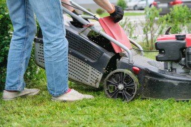 Bahçıvan kadın bacaklar çim biçme makinesi ile çim biçme çim, bir apartmanın şehir avlusu