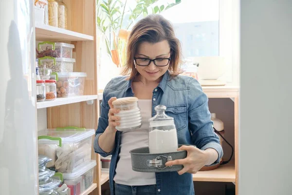 Žena středního věku vybírá potraviny ze skladu v kuchyni — Stock fotografie