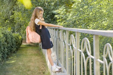 Okul bahçesinde çit yakınında okul üniforması sırt çantası ile Kız kız öğrenci sarışın