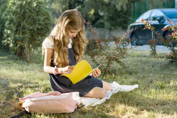 Utomhus porträtt av Schoolgirl sitter på gräset Läs skola anteckningsbok. Starta skolan — Stockfoto