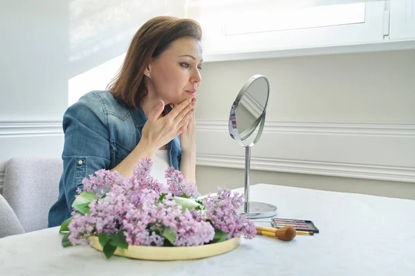 Retrato de mulher madura com espelho de maquiagem massageando seu rosto e pescoço, linda mulher de 40 anos — Fotografia de Stock