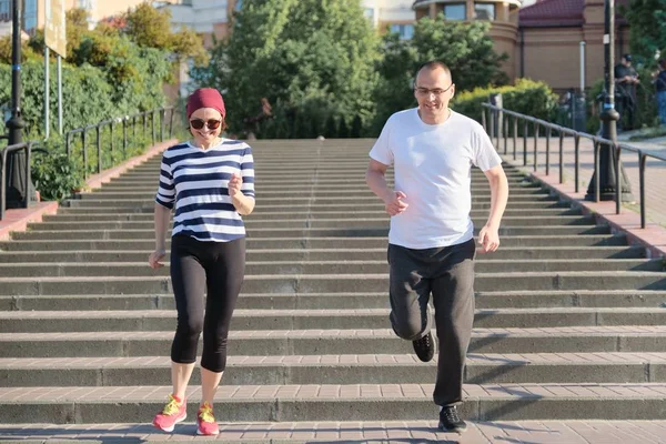 Olgun çiftin aktif sağlıklı yaşam tarzı. Orta yaşlı erkek ve kadın üst katta koşuyor — Stok fotoğraf