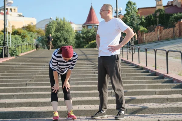 Érett pár a városban, közel a lépcsőn, középkorú férfi és nő a Sportruházat beszélő pihenő után fut — Stock Fotó